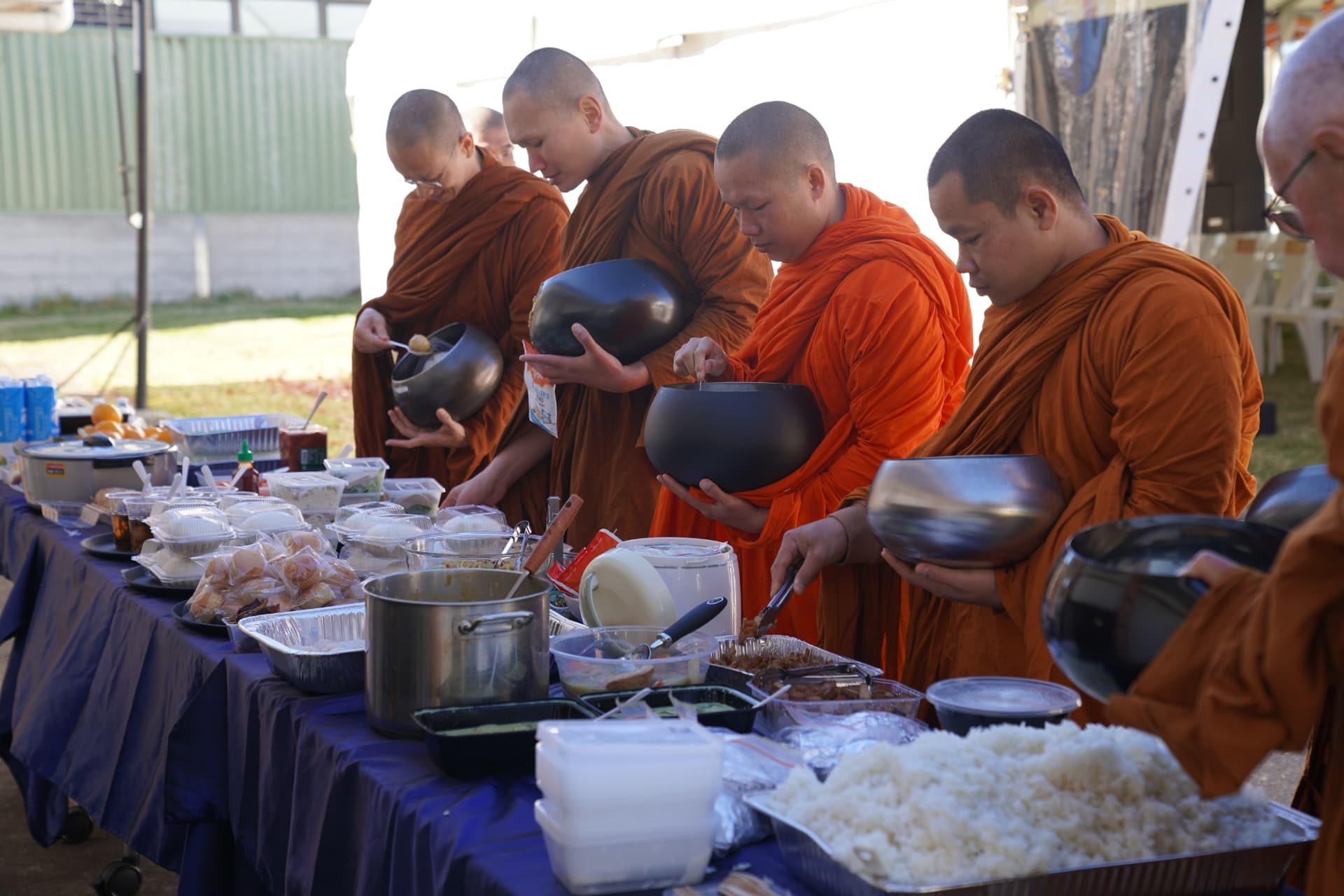 Lay people offering food into an alms bowl